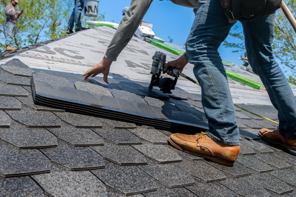 Contractor installing asphalt shingles, highlighting roof replacement material options comparison