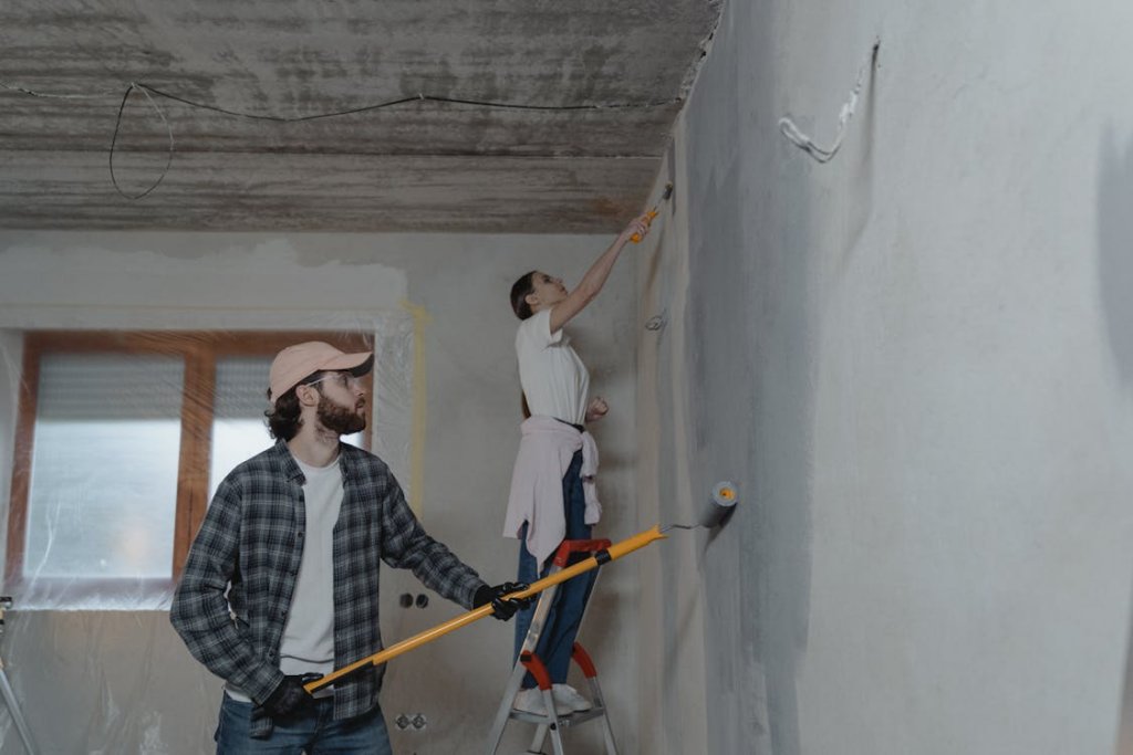 Homeowners painting walls illustrating DIY vs hiring a contractor cost comparison