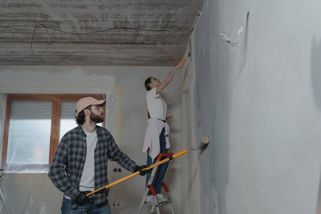 Homeowners painting walls illustrating DIY vs hiring a contractor cost comparison