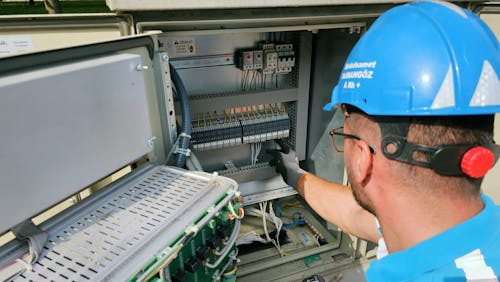 Electrician inspecting breaker panel while evaluating whole home rewiring signs